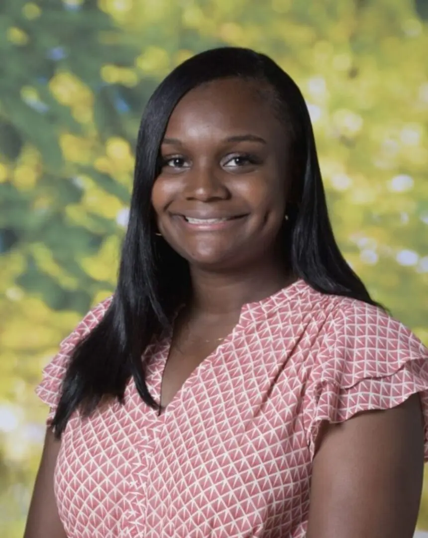 A woman in pink and white shirt smiling for the camera.